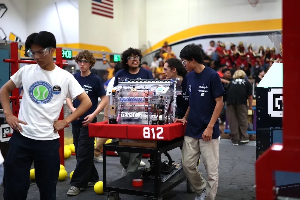 Team 812 students and a mentor moving their competition robot through the arena.