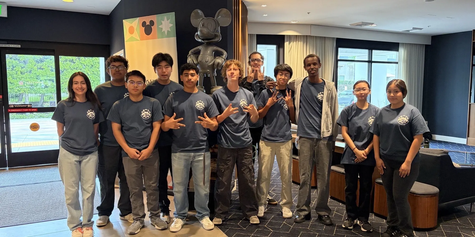 Team 812 members in matching team shirts posing together in a hotel lobby.