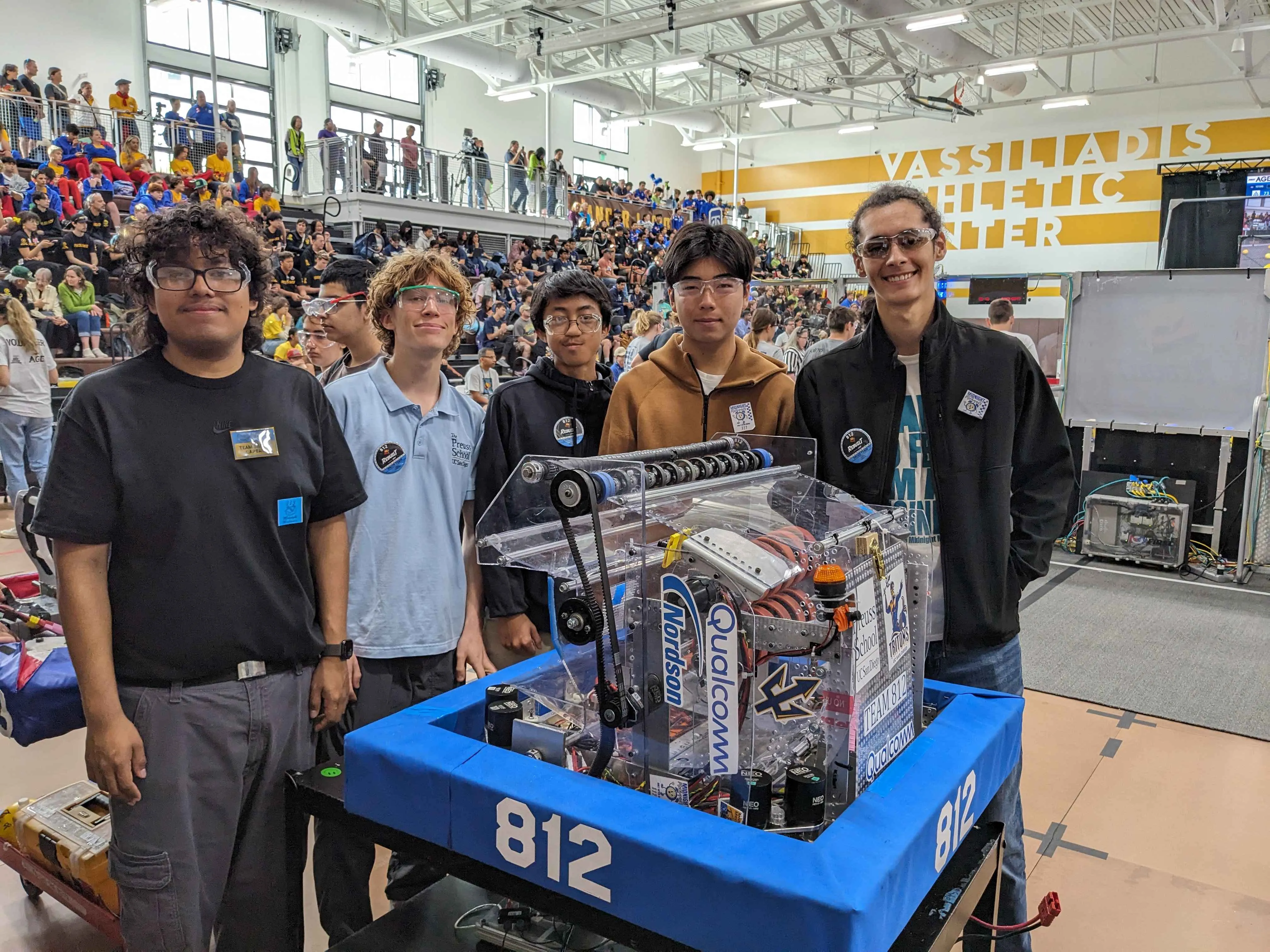 Team 812 members posing with their competition robot in the arena at a REBUILT event.